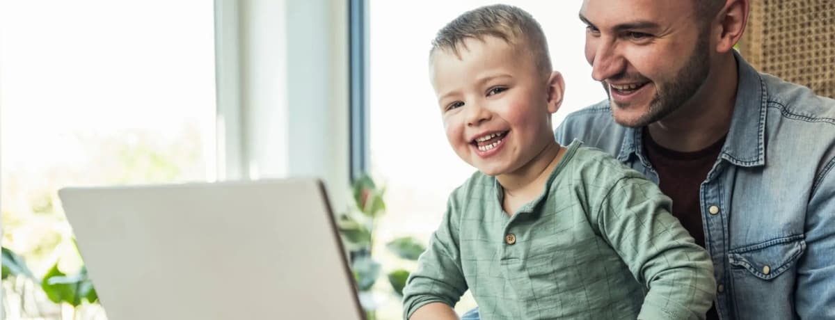 Parent and child smiling while using a laptop together
